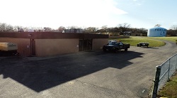 Tall Oaks building with a truck out front and a water tub out back